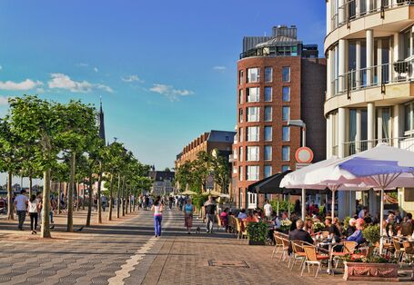 Fußgängerzone in der Stadt, in der Menschen spazierengehen, joggen oder draußen in Cafés sitzen
