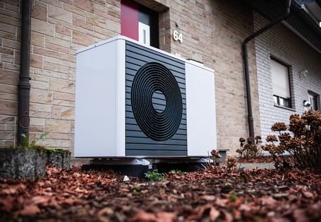 Außeneinheit einer Wärmepumpe im Vorgarten eines Reihenhauses