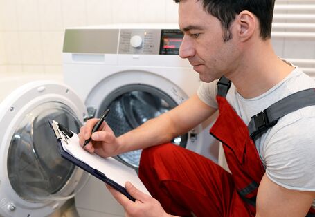 Monteur macht sich Notizen zu einer defekten Waschmaschine