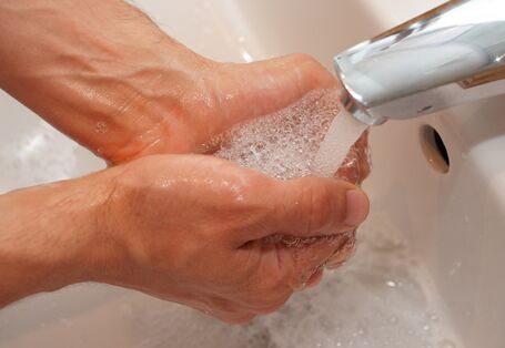 zwei Hände unter dem Wasserhahn