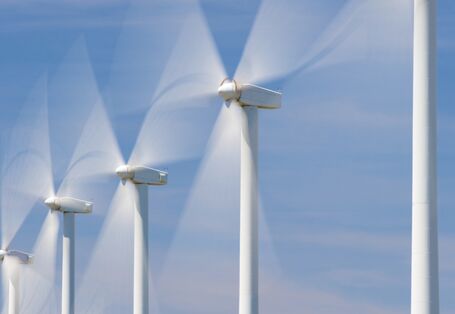 Windkraftanlagen drehen sich vor blauem Himmel