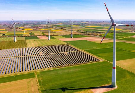 Wind turbines between agricultural land and a solar park