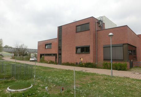 Ein Backsteingebäude, davor Wiese