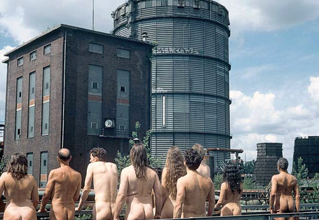 nackte Gruppe von Menschen mit Blickrichtung weg vom Betrachter, in Richtung eines Hauses blickend