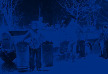 Mehrere Arbeiter entleeren Eimer in ein Müllfahrzeug