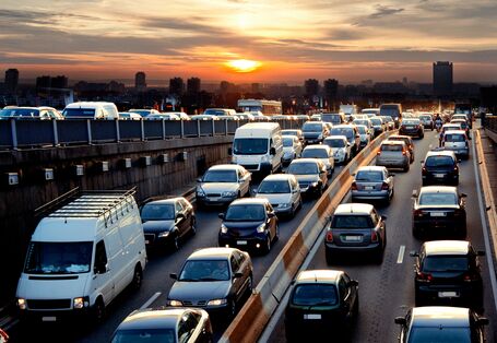 Stau auf der Autobahn am Abend. Ein Sonnenuntergang ist am Horizont zu sehen. 