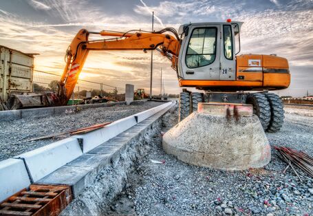 Bagger auf der Baustelle räumt Abfall in Container