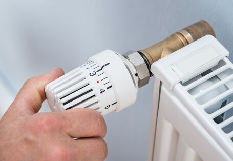 Mann dreht am Heizkörperventil