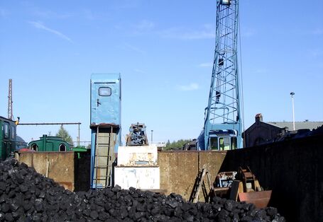 Steinkohleberg am Bahnhof zur Beladung alter Dampfloks, die im Hintergrund zu sehen sind