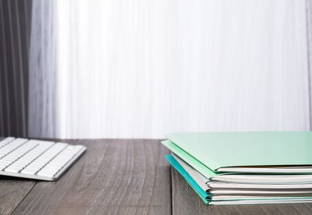 Tastatur und grüne Mappen auf einem Tisch