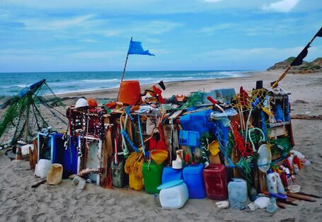 Ein Schiffskutter behängt mit bunten Plastikkanistern und -flaschen am Strand