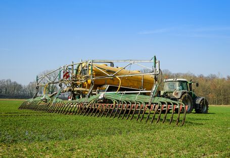 Ein Traktor bringt Gülle auf einem Feld aus