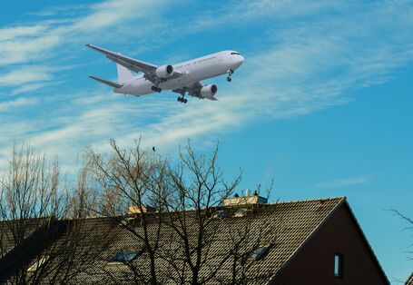 Ein Flugzeug fliegt über ein Wohngebiet.