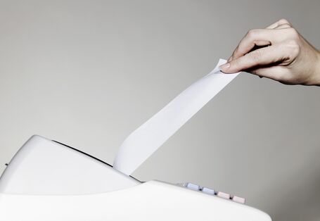 Eine Kasse, aus der ein Kassenbon ausgedruckt wird.