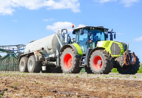 Ein Traktor bringt Gülle auf einem Feld aus