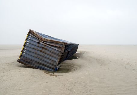 Ein havarierter Schiffscontainer liegt an einem Sandstrand.