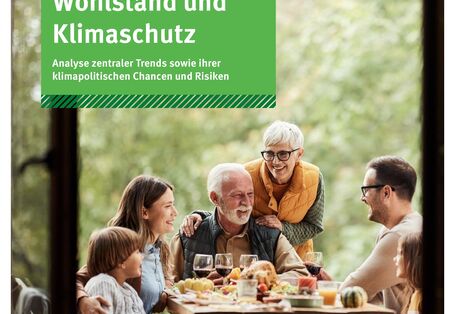 Menschen sitzen um einen gedeckten Tisch im Freien