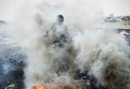 Mensch in Rauchschwaden bei der Verbrennung von Schrott.