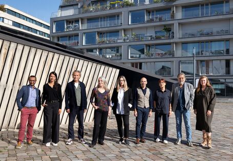 Die Jury steht vor einem Gebäude.