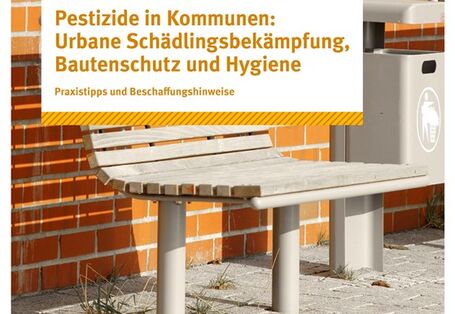 Eine Sitzbank und ein Mülleimer vor einer Backsteinmauer