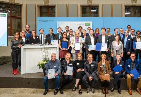 Die Preisträgerprojekte und Nominierten des Bundespreises "Blauer Kompass" 2022 stehen fest und posieren gemeinsam auf der Bühne. Der mit 25.000 Euro dotierte Preis geht jeweils an herausragende Klimanpassungsprojekte in den Bereichen Hochwasserschutz, Landwirtschaft, Handwerk sowie Umweltbildung und ländliche Entwicklung.