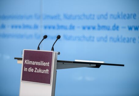 Ein leeres Sprechpodest mit zwei Mikros und einem Schild Klimaresilient in die Zukunft