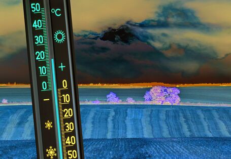 Das Bild zeigt im Vordergrund ein Thermometer, das 20 °C anzeigt. Die im Hintergrund liegende Landschaft ist geprägt von intensiver Landwirtschaft und zeigt ein abgeerntetes Getreidefeld. Dunkle Wolken verdecken die Sonne, die im Hintergrund hinter den dunklen Wolken den Himmel erhellt.