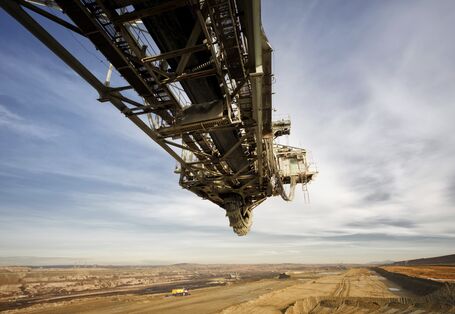 Stillstehender Schauffelradbagger auf einem Kohletagebau, man sieht bewölkten Himmel und den Tagebau, bei dem Kohle abgebaut wird