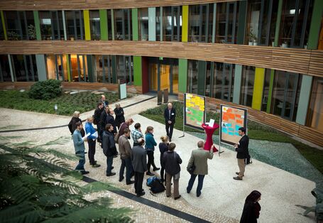 Teilnehmer stehen im Forum des Umweltbundesamtes vor den Präsentationswänden