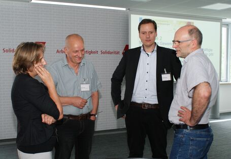 Vier Teilnehmer stehen diskutierend zusammen und schauen freundlich zueinander.