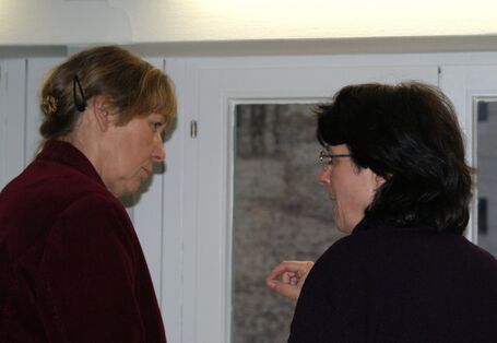 Zwei Teilnehmende stehen vor dem Fenster im Dialog miteinander.