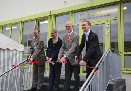 Zur Eröffnung der Großküche durchschneiden vier Personen ein rotes Band.