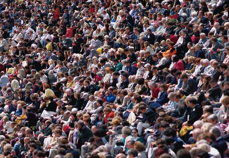 Viele Menschen sitzen nebeneinander und schauen in die selbe Richtung