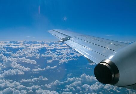 rechter Flugzeugflügel über den Wolken bei blauem Himmel