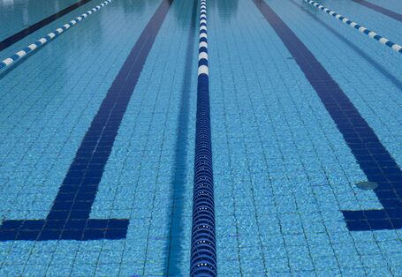 Das Wasserbecken eines Schwimmbades, wo die Bahnen durch schwimmende Abgrenzungen voneinander abgetrennt sind. Nahaufnahme