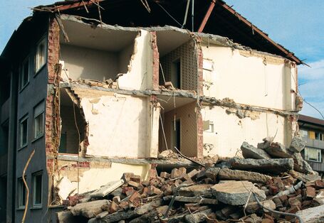 Hausabriss mit Bauschutt davor