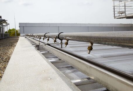 Dach wird über Rohrleitung mit Düsen mit Wasser besprenkelt.