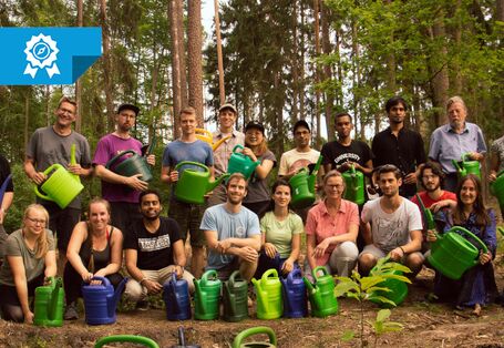 Gruppenbild von Freiwilligen bei der ersten Gießaktion. Die abgebildeten Personen halten Gießkannen in den Händen. Sie stehen im Wald.