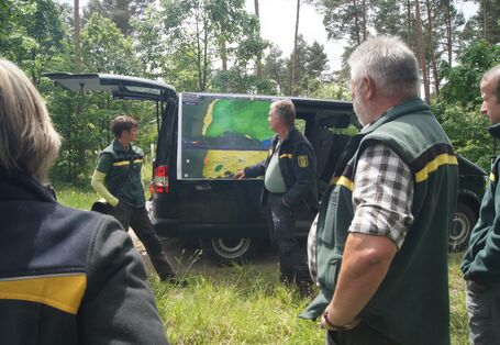 Forstmitarbeiter betrachten eine Karte im Freien.