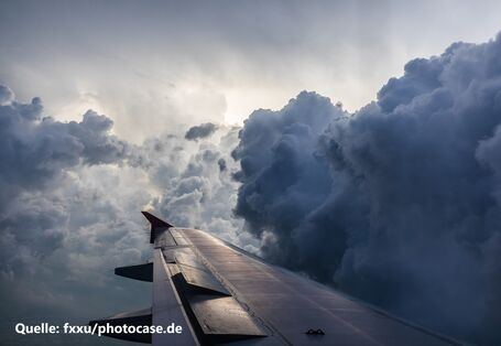Fotografie eines Flügels eines Flugzeugs im Flug. Der umgebende Himmel ist voller dunkler Wolken.