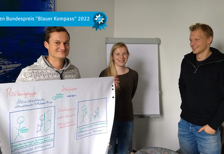 Das Bild zeigt drei Studierende mit Entwurf Poster. Präsentation der Gruppenarbeit im Workshop Klimawandel und Gesundheit im Ministerium für Arbeit, Soziales und Integration.