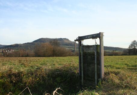 Mittig im Bild steht eine Kurbelschütz (Regulierungsvorrichtung mit Kurbel). Die senkrechte Platte, die den Graben absperren würde, ist hochgekurbelt.