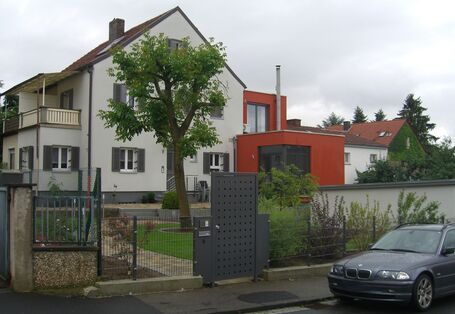 Die Ansicht eines Einfamilienhauses durch den Garten.