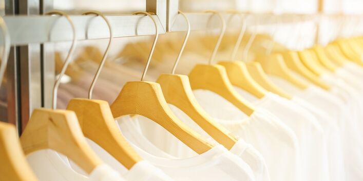 Weiße T-Shirts auf Bügeln aufgehängt in einem Geschäft