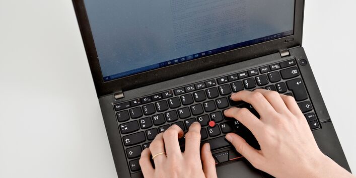 Eine Person tippt auf einer Laptop-Tastatur.
