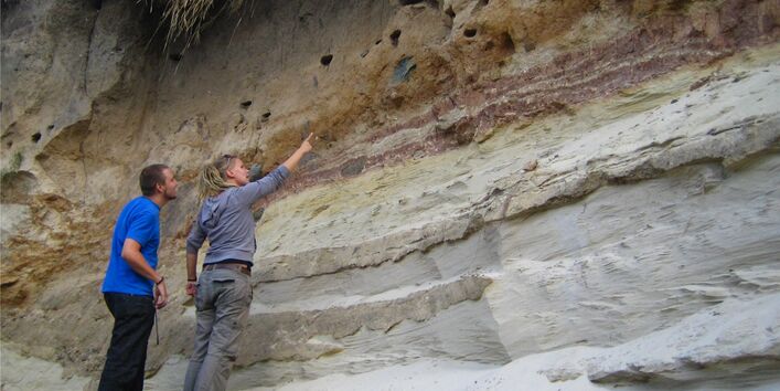 Ein Mann und eine Frau sehen sich verschiedene Bodenschichten in freier Natur an