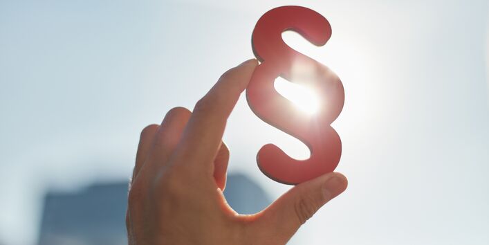 Hand mit Paragrafenzeichen