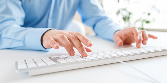 Mann tippt auf einer Computertatstatur.