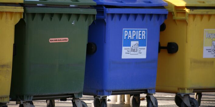 Müllcontainer in grün, blau und gelb für verschiedene Abfälle.