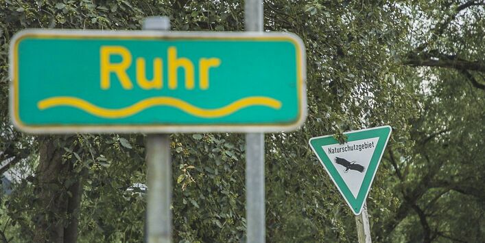 Foto: Ein Schild mit der Aufschrift „Ruhr“. Im Hintergrund ein Schild mit der Aufschrift „Naturschutzgebiet“.